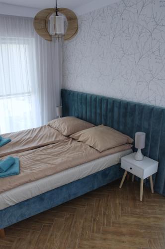 a bed with a blue headboard in a bedroom at Apartamenty na skraju lasu in Ustka
