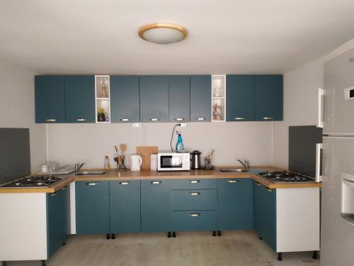 a kitchen with blue cabinets and a microwave at AlmaVille Mamaia in Mamaia Nord