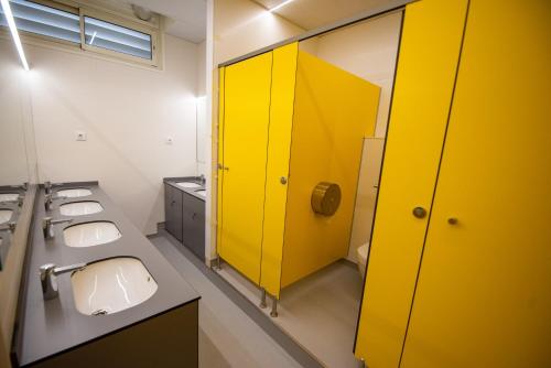 a bathroom with three sinks and a yellow door at Alberg Barcelona Xanascat in Barcelona