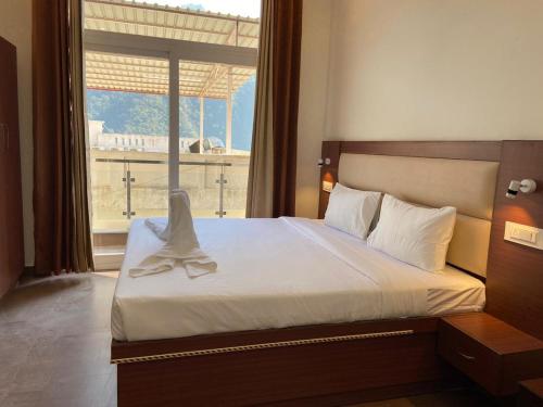 a bedroom with a bed with a large window at Hotel The Shivaay - Delight Inn Rishikesh in Rishīkesh