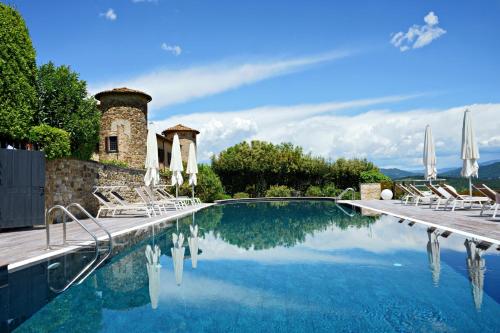 une piscine avec des chaises et un bâtiment dans l'établissement Castello Di Gabbiano, à Mercatale Val Di Pesa