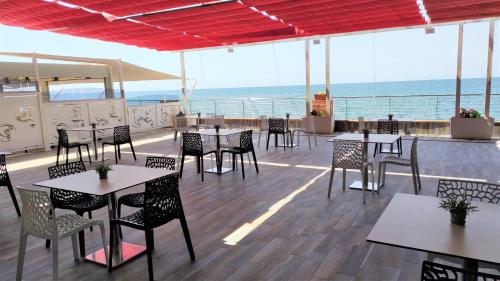 um restaurante com mesas e cadeiras e o oceano em Hotel Centro Congressi Polo Nautico em Salerno