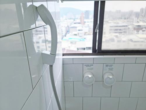 a bathroom with a window and a white tiled wall at Paper Plane Hostel in Kaohsiung