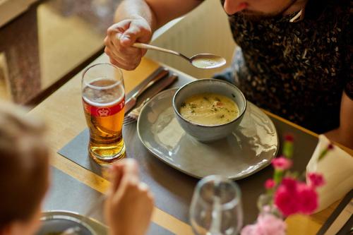 a person eating food with a bowl of soup and a glass of beer at Hotel Mazury in Giżycko