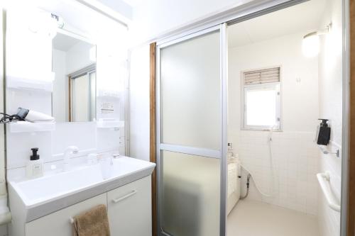 a white bathroom with a sink and a shower at Fukuoka Condominium in Fukuoka