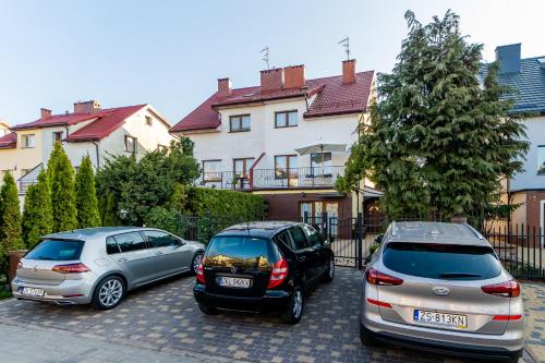 three cars parked in a parking lot in front of a house at Pokoje goscinne in Kołobrzeg