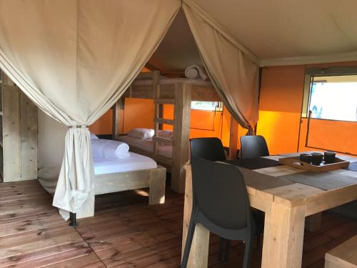 a room with a table and a bed and a dining room at Budget Glamping Safaritent - Mas de Mourgues in Vauvert