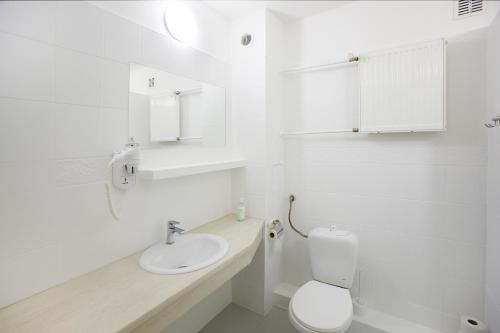 a white bathroom with a toilet and a sink at Hotel Mazury in Giżycko