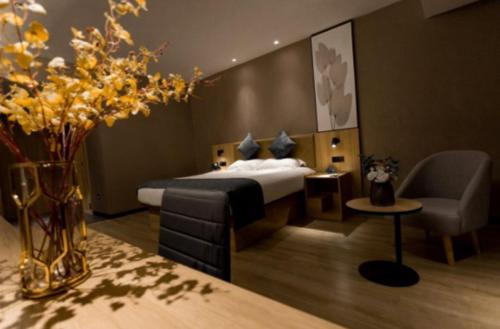 1 dormitorio con 1 cama, 1 silla y flores en GreenTree Inn Jiangsu Suzhou Changshu Fuchunjiang International Qipeicheng Road Express Hotel, en Changshu
