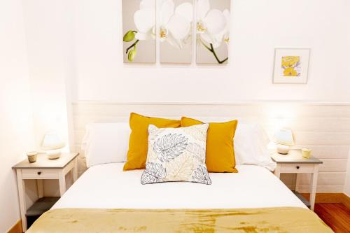 a bedroom with a white bed with yellow pillows at Dolaretxe apartment by People Rentals in Bilbao