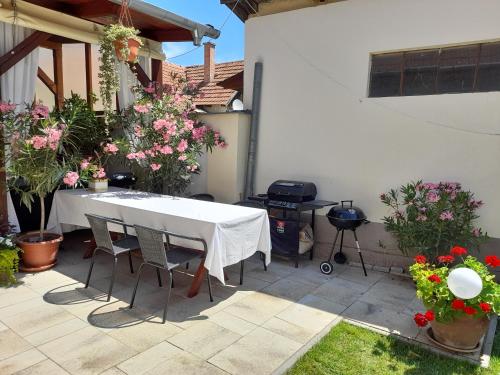 a white table and chairs on a patio with flowers at Aranka Apartman in Gyula