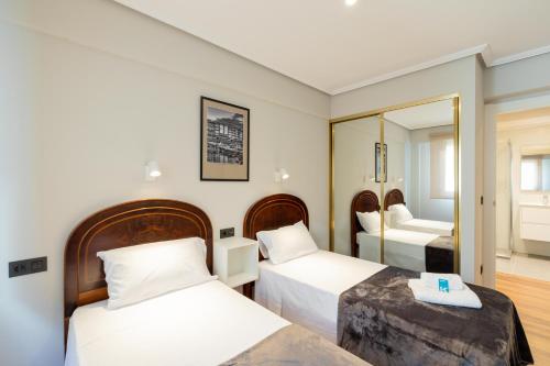 una camera d'albergo con due letti e uno specchio di Agirre - BasKey rentals a Lekeitio