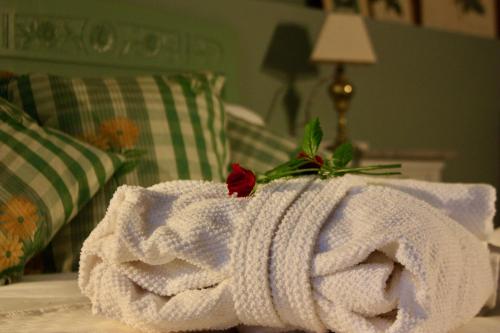 un asciugamano bianco su un letto con una rosa sopra di Casapaletti Country House ad Alfiano Natta