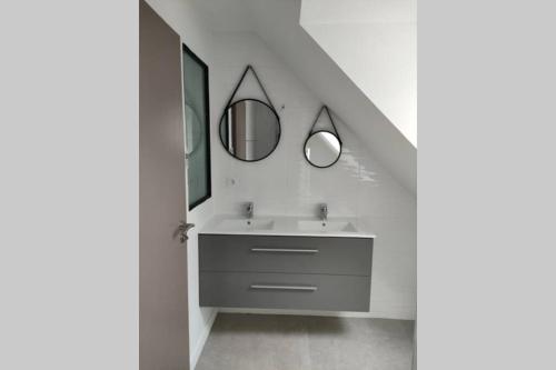 ein Bad mit einem Waschbecken und 2 Spiegeln in der Unterkunft Gite de Kerampif in Pluherlin