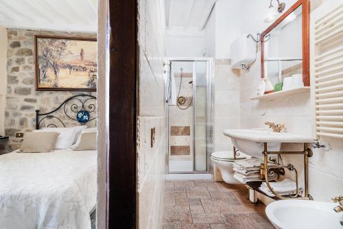 un bagno con lavandino, servizi igienici e un letto di Albergo Il Giglio a Montalcino