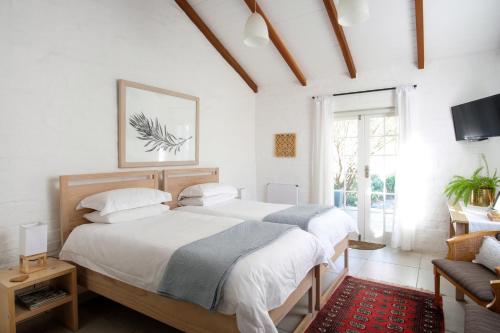 two beds in a white bedroom with a window at Kogman & Keisie Guest Farm in Montagu