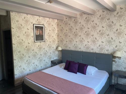 - une chambre avec un grand lit et des oreillers violets dans l'établissement HOTEL ERMITAGE, aux Angles (Gard)