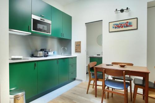 une cuisine avec des placards verts et une table en bois dans l'établissement Résidence Le Marais by Studio prestige, à Paris