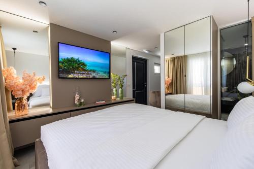 a bedroom with a large white bed and a flat screen tv at Villa Nina - Apartments with pool near the sea in Rabac