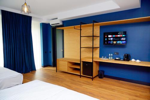 a bedroom with a bed and a tv on a blue wall at Borjomi Bridge Hotel in Borjomi