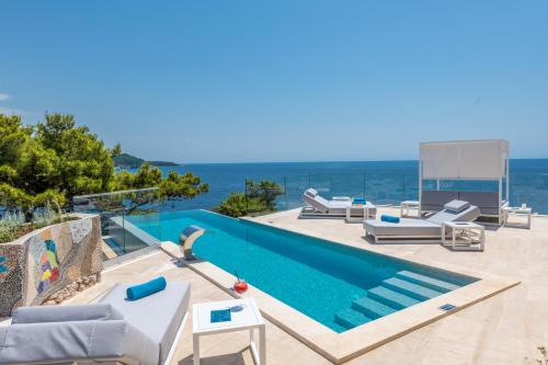 uma piscina com espreguiçadeiras e uma mesa em Villa Orabelle em Dubrovnik