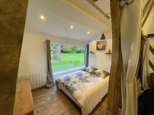 a bedroom with a bed and a large window at Les Gites de Claire in Saint-Gâtien-des-Bois