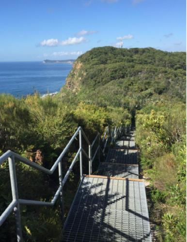 a staircase leading up to a hill with the ocean at Bay House Motel in Bateau Bay
