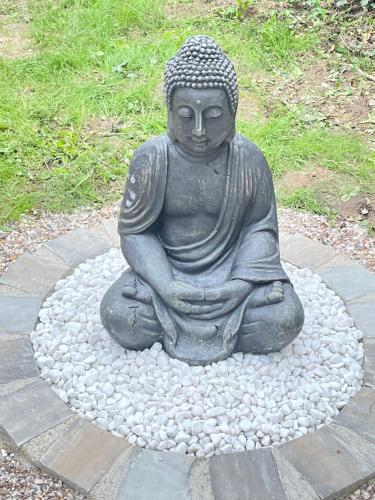 a statue sitting on a circle of rocks at Les Gites de Claire in Saint-Gâtien-des-Bois