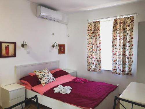 um quarto com uma cama com lençóis cor-de-rosa e uma janela em Diána Apartman Bogács em Bogács