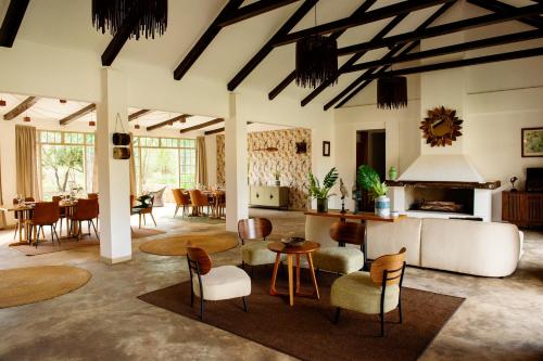 a living room with tables and chairs and a fireplace at The Safari House in Usa River