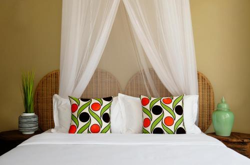 a bedroom with a bed with white sheets and pillows at The Safari House in Usa River