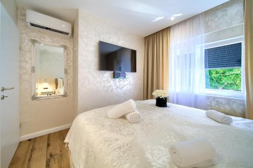 a bedroom with a white bed with a tv on the wall at Luxury Apartments JF in Rab