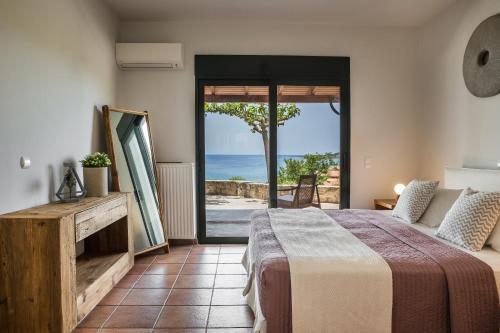a bedroom with a bed and a view of the ocean at Alekos Beach Houses-Eternity in Xi