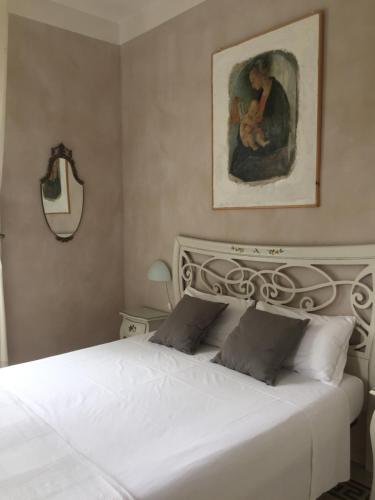 a bedroom with a white bed with a painting on the wall at Villa Liberty Urbino in Urbino