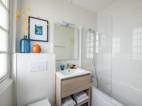 La salle de bains blanche est pourvue d'un lavabo et d'une douche. dans l'établissement Tour de Nesle La Rochelle Vieux Port 3 etoiles, à La Rochelle
