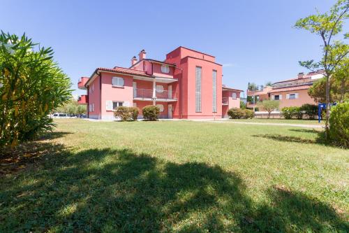 a large red building with a grassy field in front of it at Premium Marina Apartments with Sea View by Locap Group in Portorož