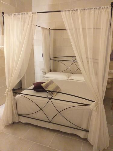 a bedroom with a canopy bed with white curtains at Dimora Assuntina Martano in Martano
