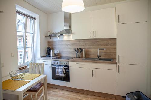 a kitchen with white cabinets and a sink and a table at Suite Barrique Zell in Zell an der Mosel