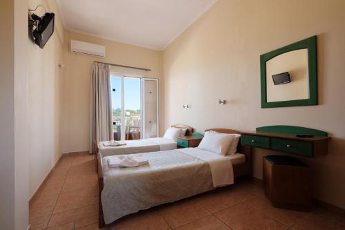 a hotel room with two beds and a mirror at Socrates Hotel in Sidari
