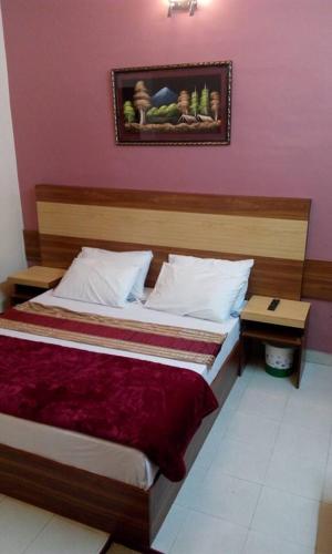 een slaapkamer met een groot bed met een houten hoofdeinde bij Springfield Guest House Rawalakot in Rāwala Kot