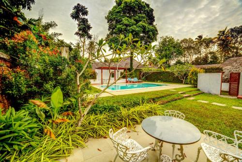 un patio con mesa, sillas y piscina en Marari Beach Resort Alleppey- CGH Earth en Alleppey
