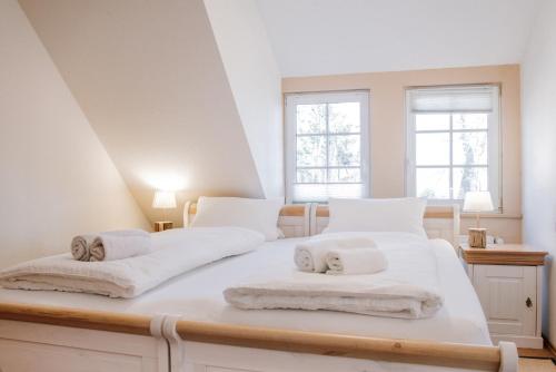 a white bedroom with two beds and two windows at Ferienhof Werner in Emstek