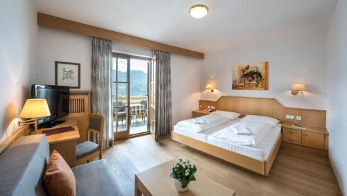 um quarto com uma cama, uma televisão e um sofá em Hotel Gasthof Waldschenke em Marlengo