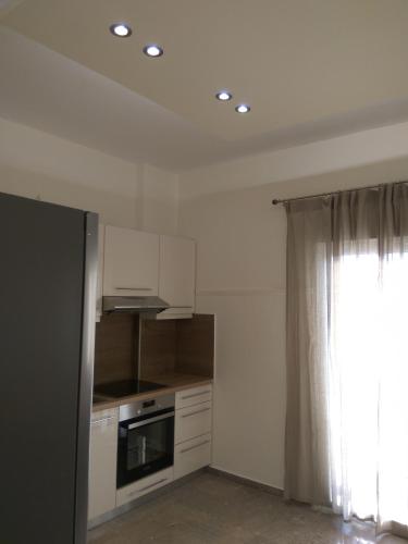 a kitchen with white cabinets and a window at NAFPAKTOS Beach luxury Suites in Nafpaktos
