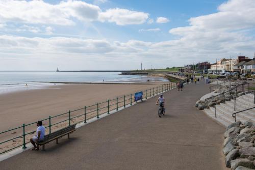 two people riding bikes on a beach next to the ocean at The Seaburn Inn - The Inn Collection Group in Sunderland