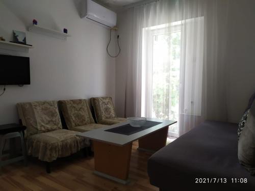 a living room with a couch and a table and a window at Apartmani KiKi in Utjeha