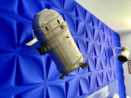 a metal object is hanging on a blue wall at toctoctoc lisboa in Lisbon