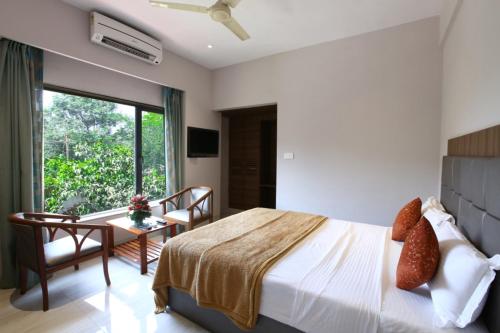 a bedroom with a bed and a table and a window at Lake View Resort Lonavala in Lonavala