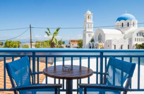 una mesa y 2 sillas en un balcón con una mezquita en Saronis Hotel Agistri - Adults Only en Skala