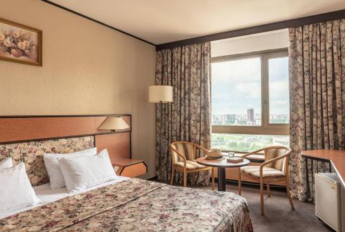 モスクワにあるCosmos Club Hotelのベッドとテーブルが備わるホテルルームです。